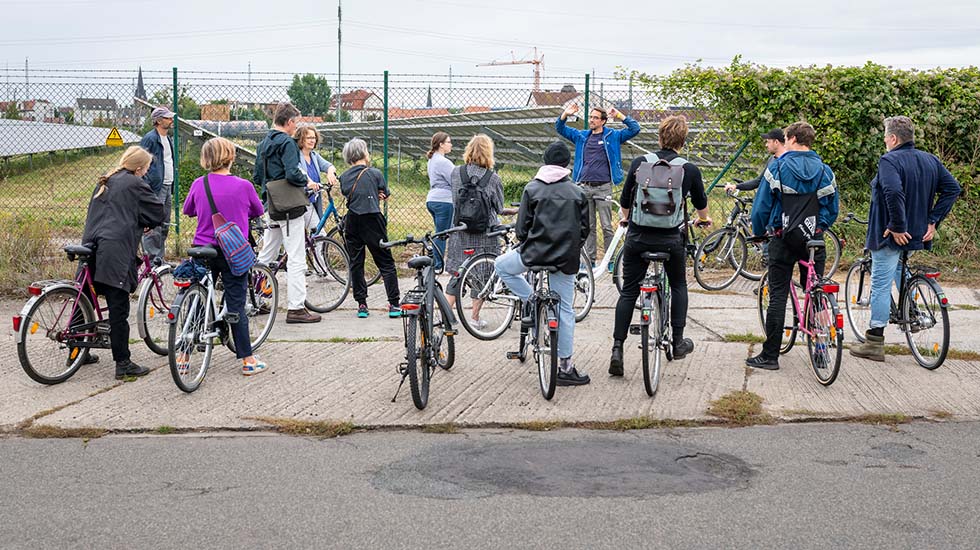 Menschen mit Fahrrädern schauen auf den Solarpark bei Bitterfeld.