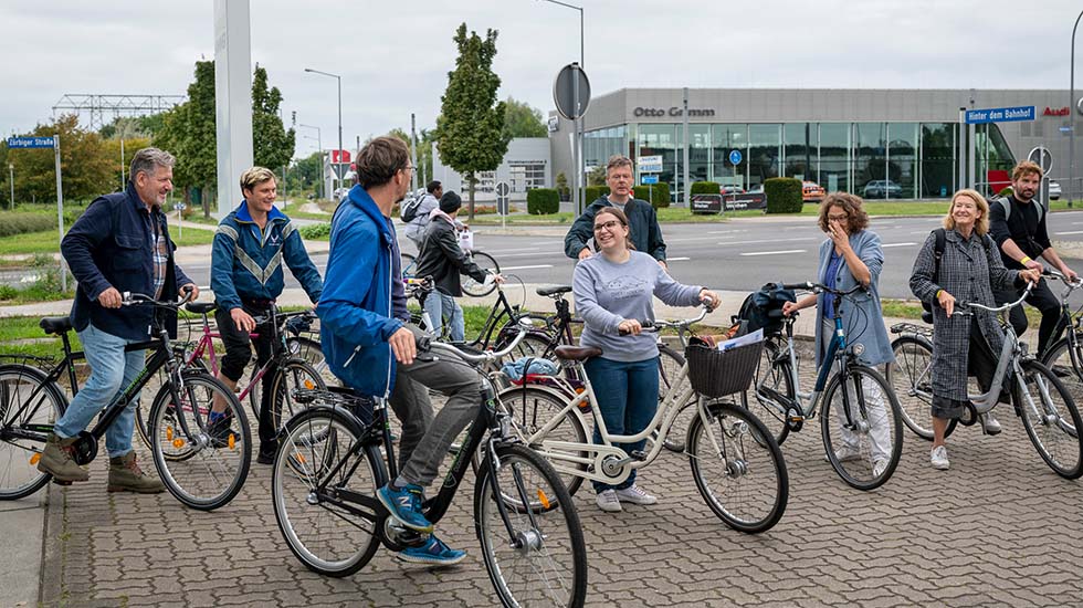 Aljoscha Begrich, Teil der künstlerischen Leitung des Festivals, spricht mit eine Gruppe Fahrradfahrer:innen bei einem gemeinsamen Ausflug.