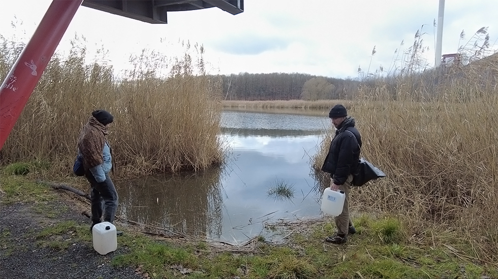 Zwei Menschen mit Kanistern am See, Standbild der Videoarbeit © privat